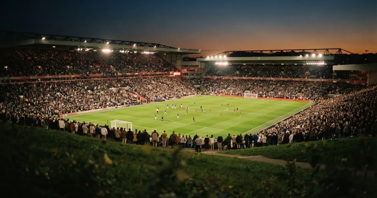 Ein Fußballstadion unter Flutlicht mit hellen Rängen, von einem Hügel aus gesehen, darüber ein dunkelblauer Abendhimmel.
