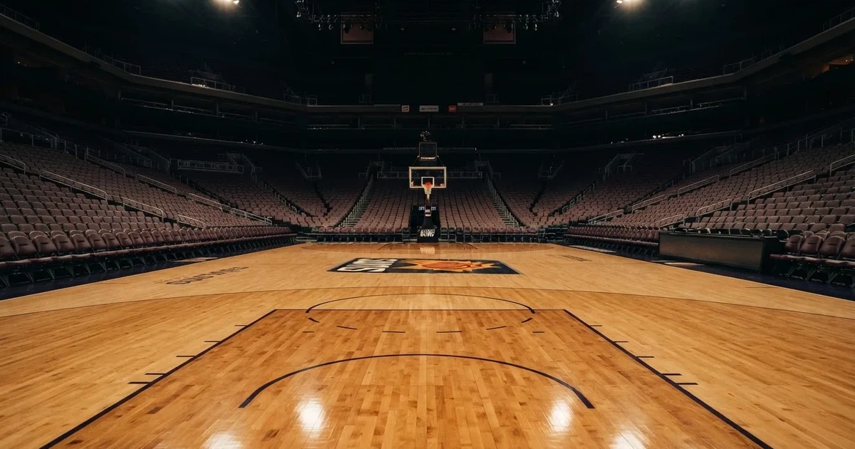 Eine leere Basketballhalle mit glänzendem Parkett und einem Korb im Hintergrund, Licht von Deckenstrahlern spiegelt sich im Boden.