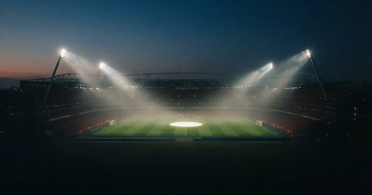 Ein leeres Stadion unter Flutlicht aus großer Entfernung gesehen, Dunst liegt über dem Rasen, die Tribünen sind nur als Lichtpunkte erkennbar.