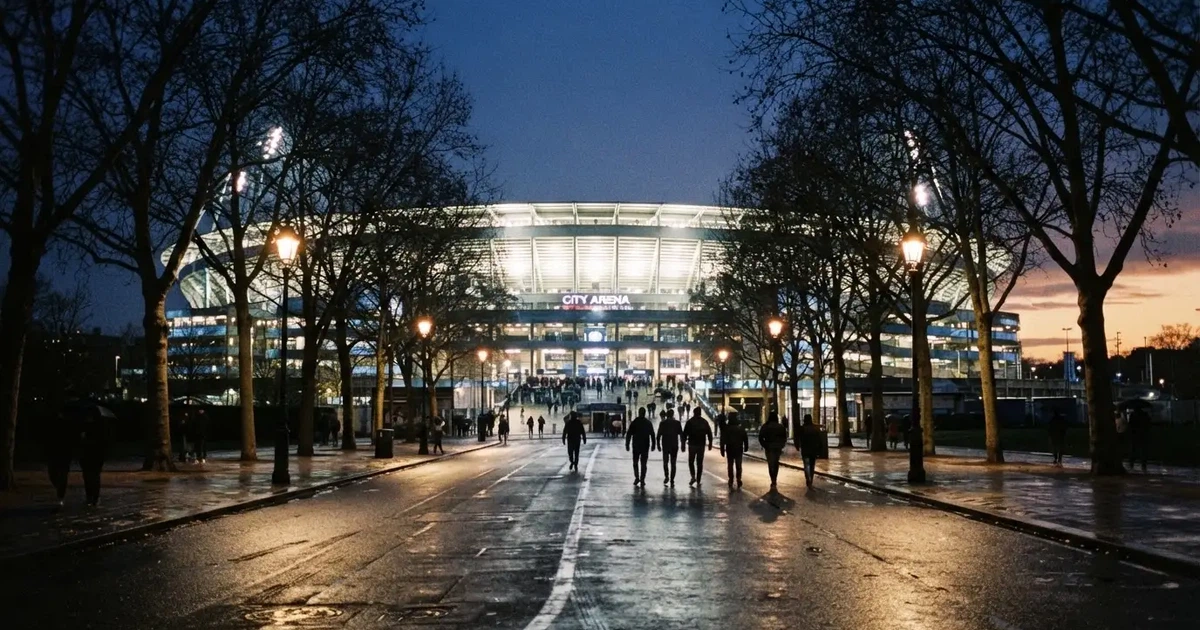 Ein großes Fußballstadion mit hell erleuchtetem Rund, aus der Ferne am Abend gesehen, davor eine breite Allee mit Laternen.